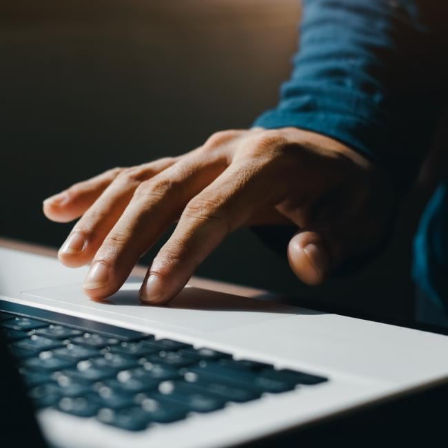 A hand is on the trackpad of a laptop